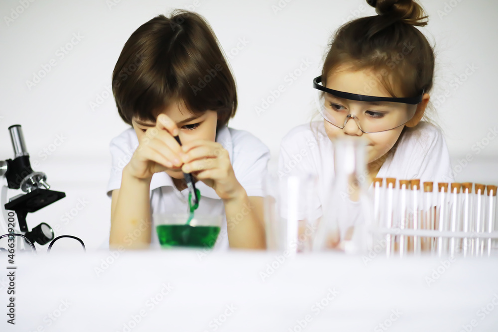 Two cute children at chemistry lesson making experiments on white background Two cute children at chemistry lesson making experiments on white background