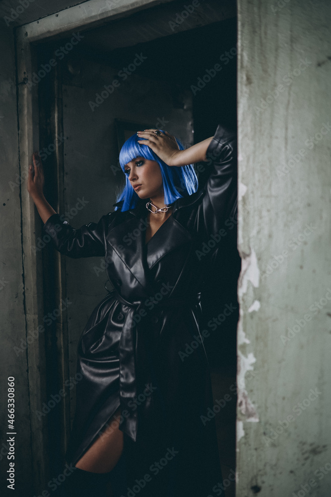 beautiful girl with blue hair in a black cloak posing in an abandoned building. Сyberpunk fashion and style.