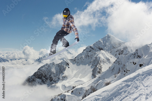 A jumping snowboarder in the mountains. Snowboarding, winter extreme sport.