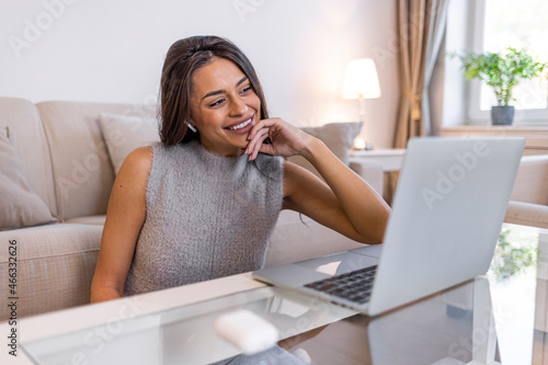 Cheerful girl student professional laughing looking away sit with laptop computer at home office table, positive woman having fun enjoy sincere emotion laughter studying working on pc