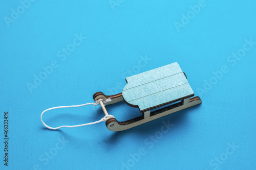 Blue wooden sled with rope on a blue background.