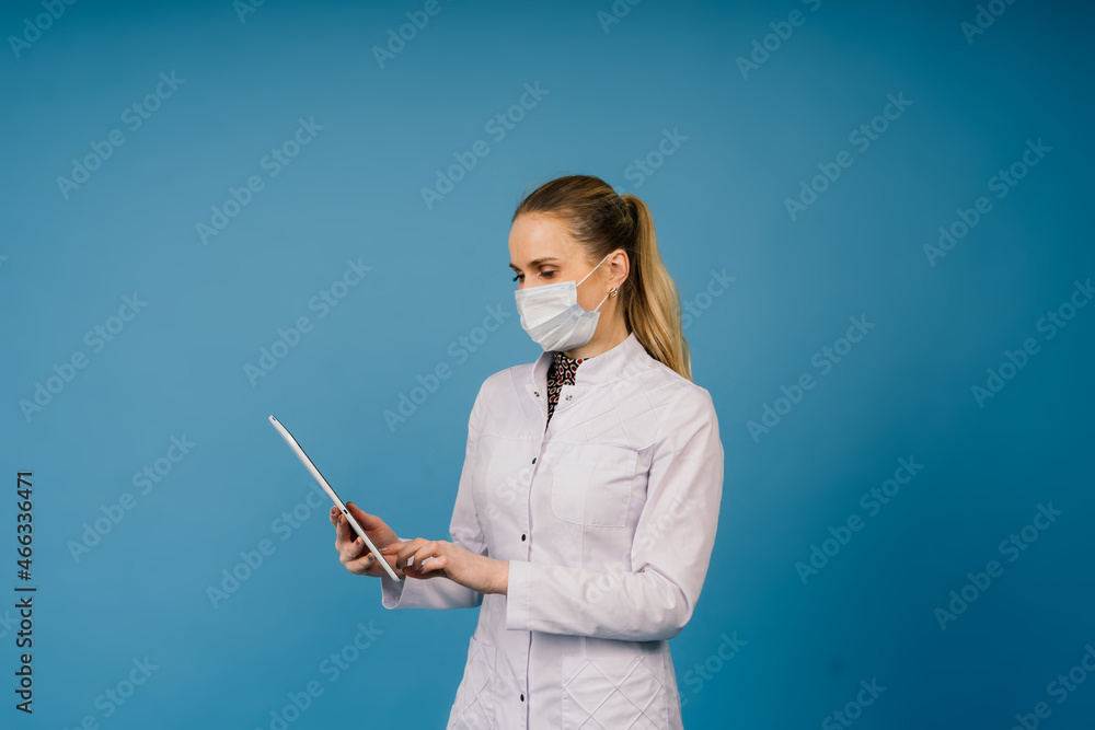 Young beautiful doctor woman in lab coat, studio shot, blue background Young beautiful doctor woman in lab coat, studio shot, blue background