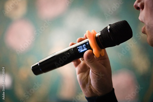 Macro view of microphone in hand of singing obscured man