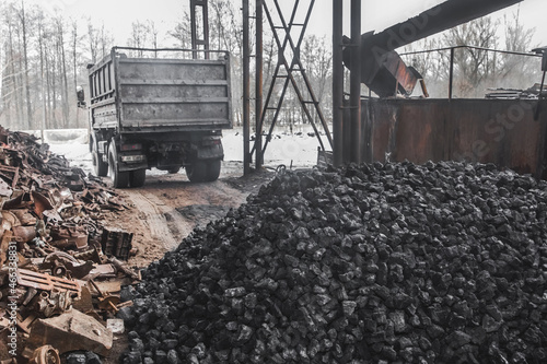 A dump truck at a landfill or on an industrial site unloaded a pile of coking coal from the body