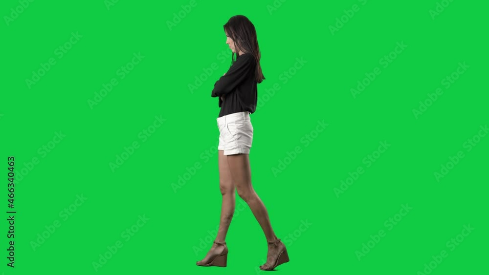 Side view of angry furious young business casual style woman walking with crossed arms. Full body isolated on green screen background Side view of angry furious young business casual style woman walking with crossed arms. Full body isolated on green screen background