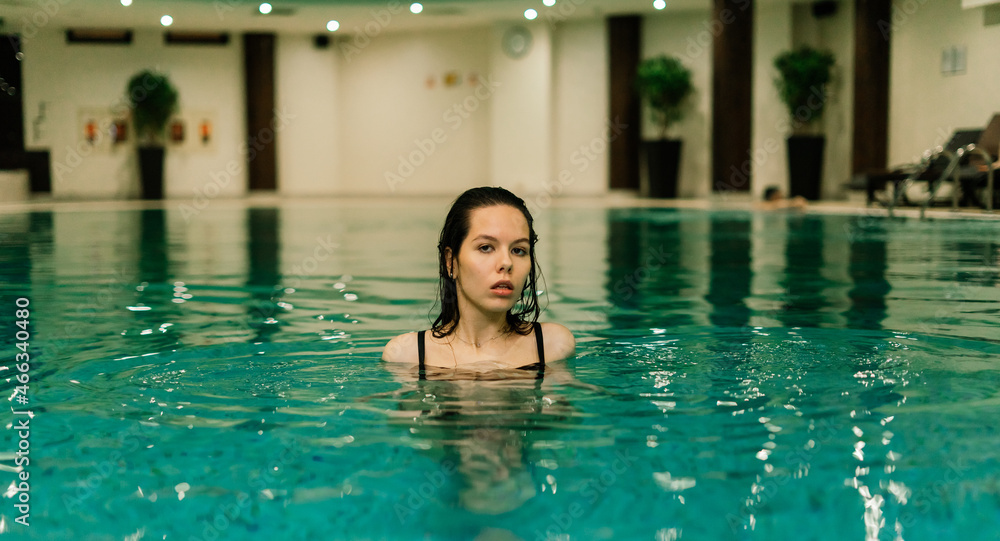 Portrait of beautiful woman in swimwear relaxing in swimming pool spa.