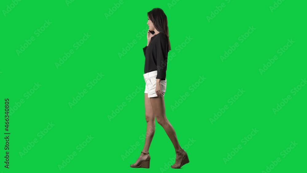 Side view of elegant young woman walking and talking on cellphone. Full body isolated on green screen background Side view of elegant young woman walking and talking on cellphone. Full body isolated on green screen background