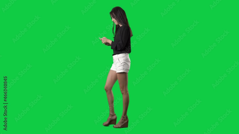 Side view of happy walking stylish business casual woman using smart phone. Full body isolated on green screen background Side view of happy walking stylish business casual woman using smart phone. Full body isolated on green screen background