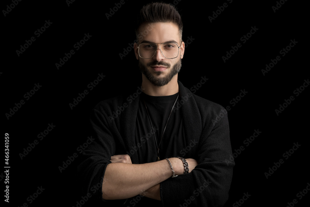 happy unshaved young man with glasses crossing arms and smiling