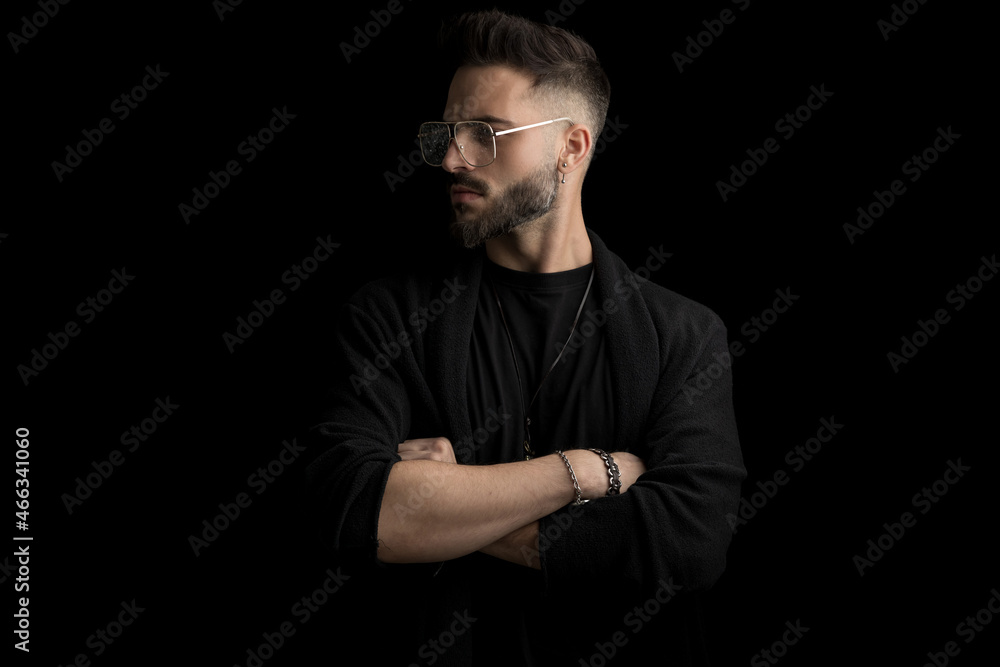 mysterious young man with glasses looking to side and crossing arms