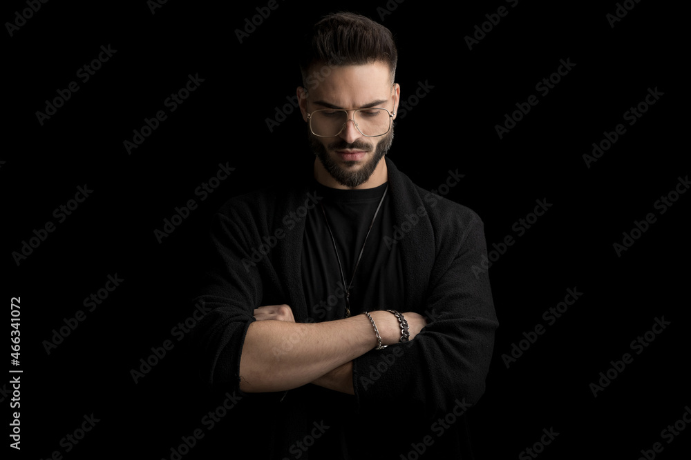 dramatic unshaved young man looking down and folding arms