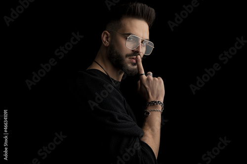 side view of sexy bearded man with glasses holding finger to mouth