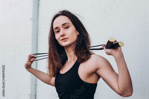sporty young lady holding a skipping rope. Close-up photo of beautiful brunette woman. 