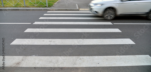 White Car is driving past a pedestrian crossing.