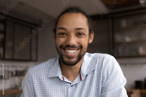 Head shot smiling young african american bearded man looking at camera, holding video call conversation, discussing working issues distantly with colleagues, male blogger streaming stories online.