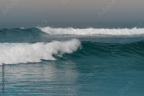 wave breaking on the beach - blue ocean with two parallel waves