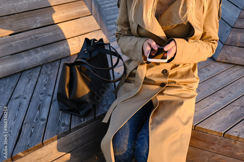 Woman is holding a modern smartphone, sending a text message or using an app on her mobile phone. Internet technology user. Smartphone close-up. Focus on the phone screen