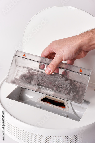 Take out the transparent dust container from the robot vacuum cleaner after cleaning the house. The container is completely clogged with dust photo