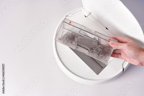 Take out the transparent dust container from the robot vacuum cleaner after cleaning the house. The container is completely clogged with dust photo