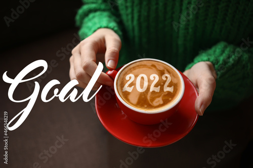 Woman with cup of tasty coffee, closeup. New Year 2022 goals