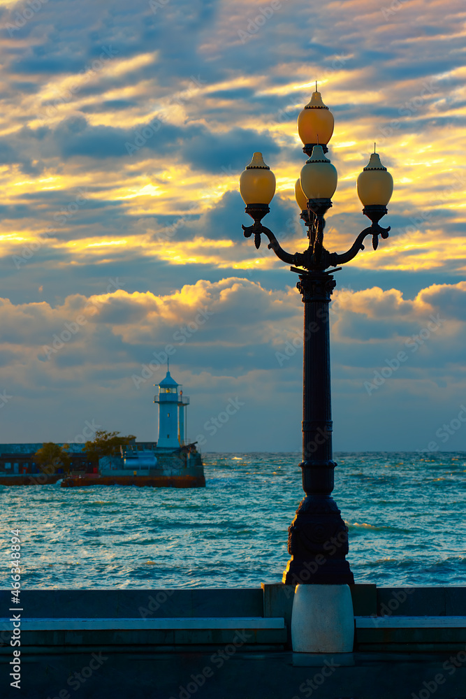 Vintage lantern on the background of the lighthouse and the sea.