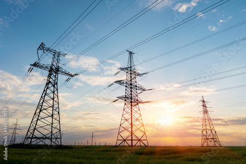 silhouette of high voltage power lines against a colorful sky at sunrise.