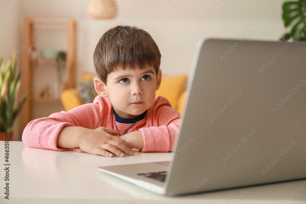 Little boy watching cartoons on laptop at table in living room Little boy watching cartoons on laptop at table in living room