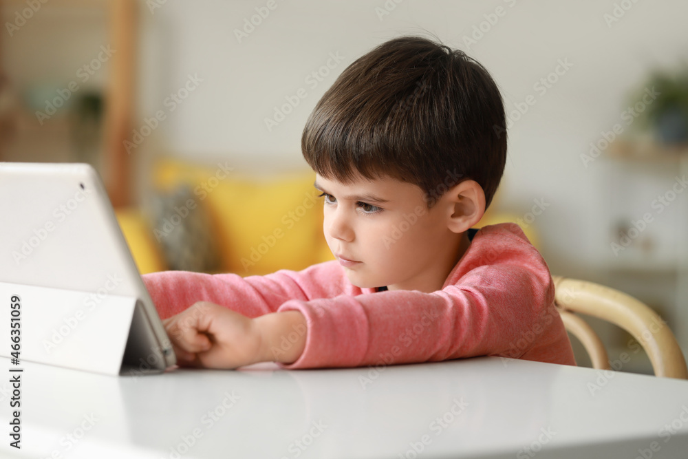 Little boy watching cartoons on tablet computer at table in living room Little boy watching cartoons on tablet computer at table in living room