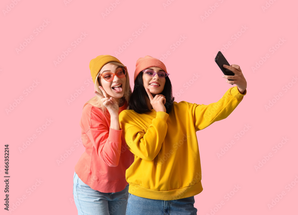 Cool young women taking selfie on color background Cool young women taking selfie on color background