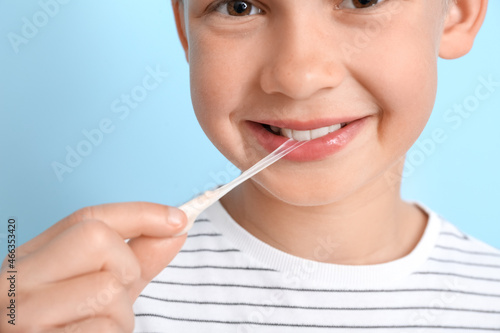 Little boy with chewing gum on blue background  closeup