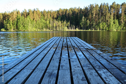Wooden pier on a forest lake at sunny day.
