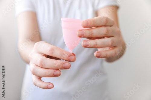 Woman hand holding pink menstrual cup Isolated on white background. Woman modern alternative eco gynecological hygiene in menstruation period. Container for blood in girl hand.