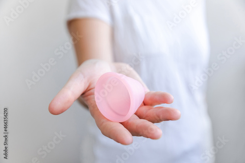 Woman hand holding pink menstrual cup Isolated on white background. Woman modern alternative eco gynecological hygiene in menstruation period. Container for blood in girl hand. photo