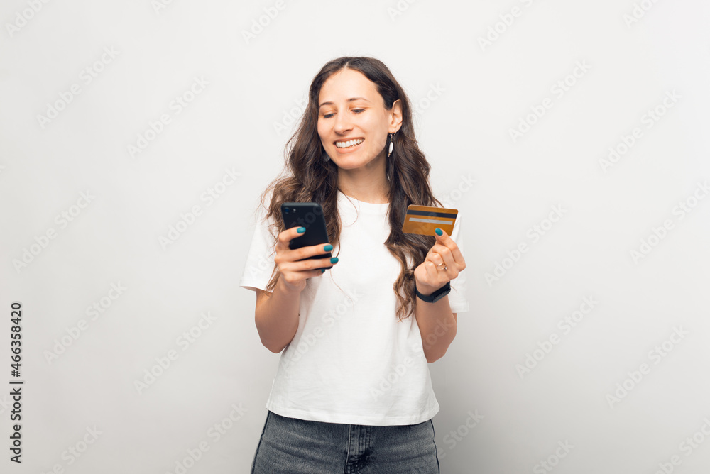 Young smiling woman is using a credit card and her phone. Young smiling woman is using a credit card and her phone.
