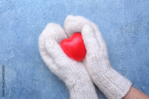 Woman in warm mittens with heart on blue background. Winter concept