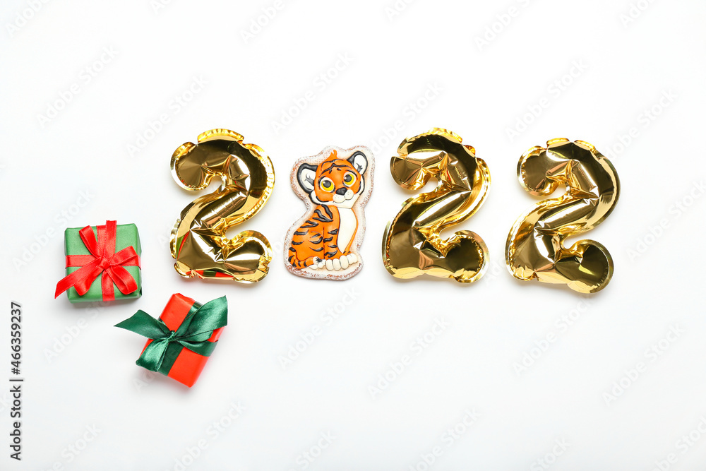Balloons in shape of figure 2022, tiger cookie and gift boxes on white background Balloons in shape of figure 2022, tiger cookie and gift boxes on white background