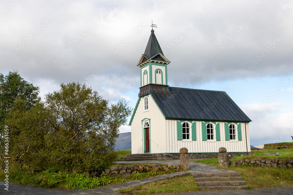 Thingvellir church in Thingvellier Park in Iceland. Cloudy sky with areas of blue. Side angle of church.