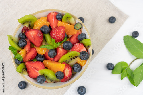 Fresh chopped fruit salad in a bowl on white background. Top view.