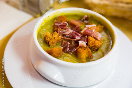 Zucchini soup puree garnished with toasted bread and ham slices