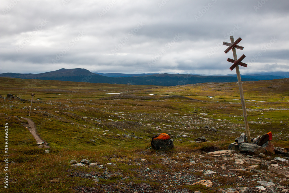 A winter snowmobile sign and an orange summer marker of Kungsleden trail between Viterskalet and Syter huts, northern Sweden, August. A winter snowmobile sign and an orange summer marker of Kungsleden trail between Viterskalet and Syter huts, northern Sweden, August.