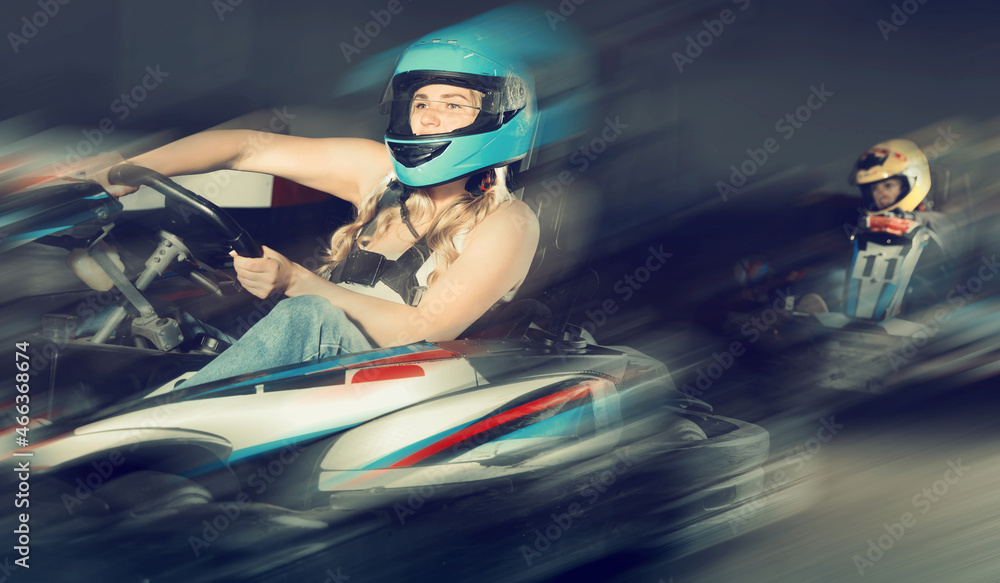 Portrait of blonde sportive woman driving racing car at kart circuit