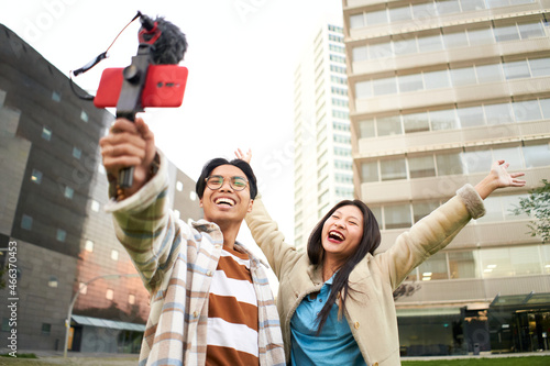 Canvas Print Happy asian couple taking a selfie in a city - Trendy young friends having fun with the technology trend - Concept of technology, friendship and influencer