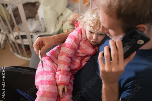 Canvas Print father holds thermometer hugging sick little girl in pajamas in the bedroom