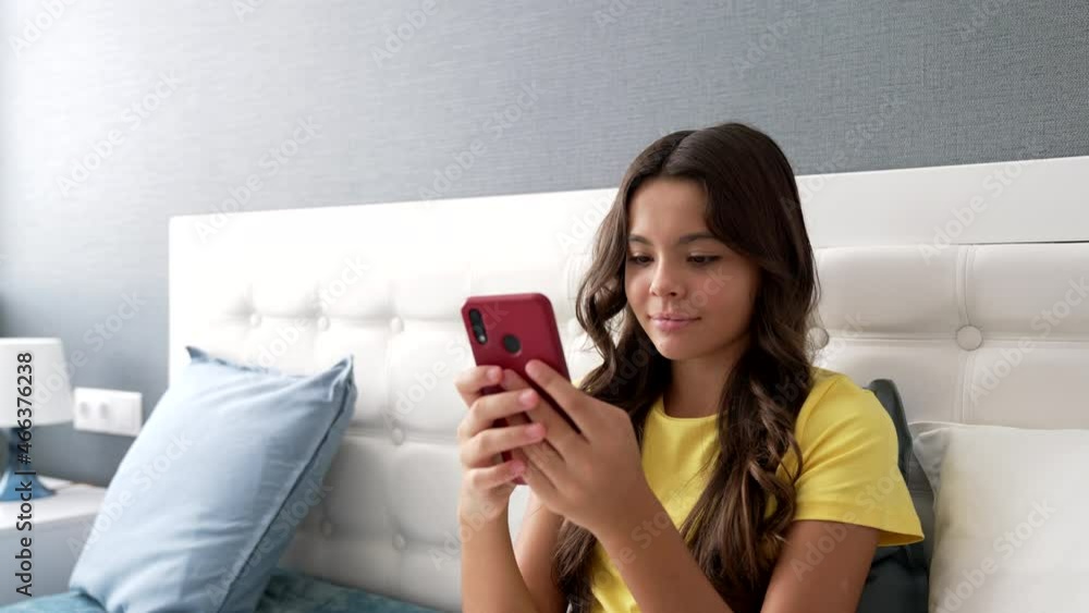 smiling teen girl typing message on mobile phone in bedroom, mobile technology smiling teen girl typing message on mobile phone in bedroom, mobile technology