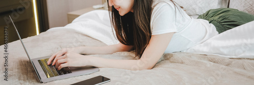 Asian young woman lying down on the bed resting browsing internet with Laptop  concept photo