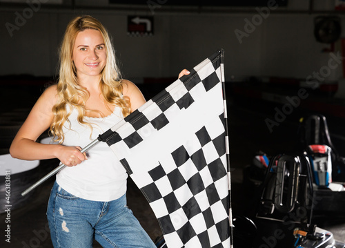 happy blonde woman with checkered race flag standing near sport car for carting © JackF