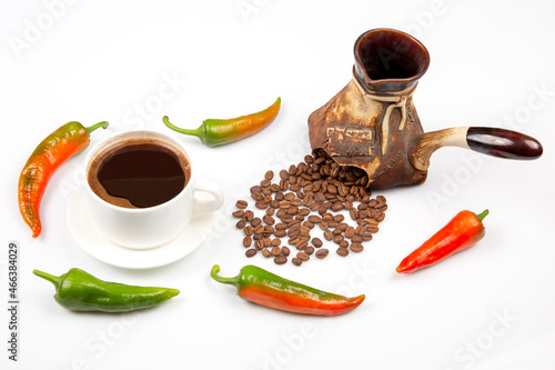 Freshly brewed hot black coffee in a white cup on a white plate next to a ceramic turkey with coffee beans. hot pepper