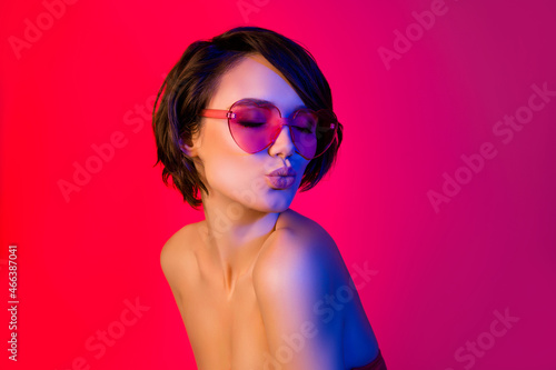 Portrait of attractive dreamy funky girl wearing specs sending air kiss isolated over bright red multicolor color background photo