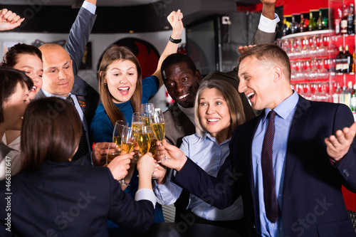 International group of cheerful smiling businesspeople toasting with champagne, having fun at office party in nightclub