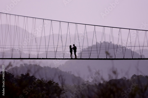 silhouette couple travel adventure on suspention bridge.